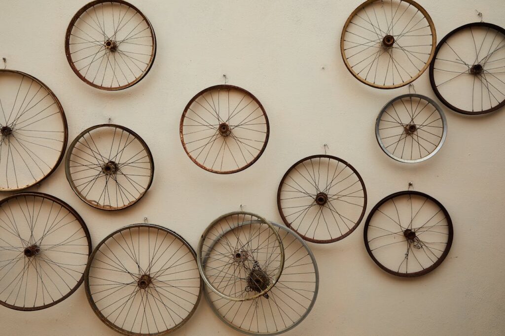 A collection of vintage bicycle wheels arranged on a wall, showcasing industrial art.